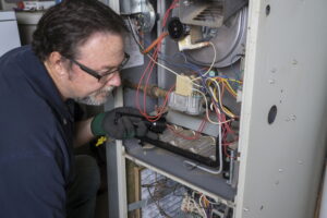 Technician-looking-over-a-gas-furnace-with-a-flashlight