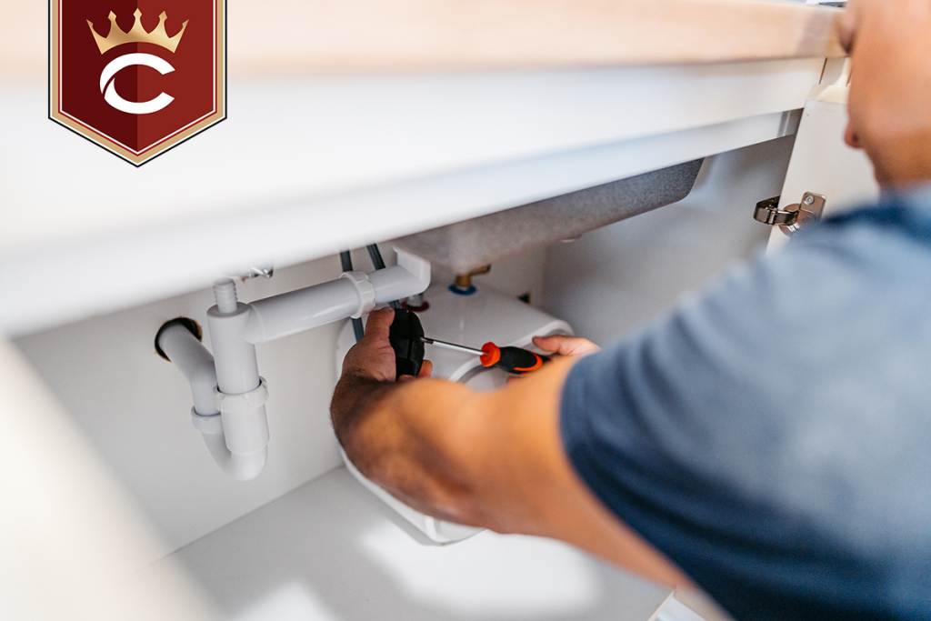 Mid-adult plumber fixing plumbing under the kitchen sink in an apartment